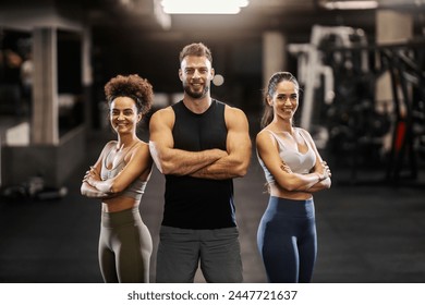 Fit sportspeople standing in a gym with arms folded and smiling while looking at the camera. - Powered by Shutterstock