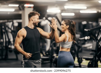 A fit sportswoman giving high five to her personal trainer in gym. Gym workout. - Powered by Shutterstock