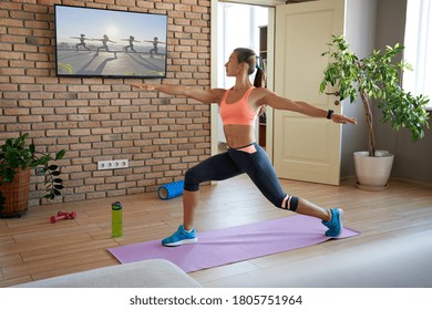 Fit Sporty Active Young Woman Learning Warrior Yoga Pose Watching Live Streaming Online Workout Exercise Training Weightloss Class Sport Tv At Home In Living Room. Fitness Tutorial  Livestream Concept