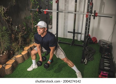 A Fit And Sporty Asian Man Does Side Dumbbell Lunges At His Home Gym. Leg Workout And Training.