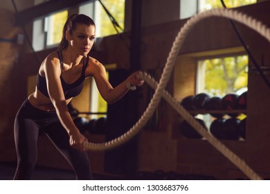 Fit, sporty and athletic sportswoman working in a gym. Woman training using battle ropes. Sports, athletics and fitness concept. - Powered by Shutterstock