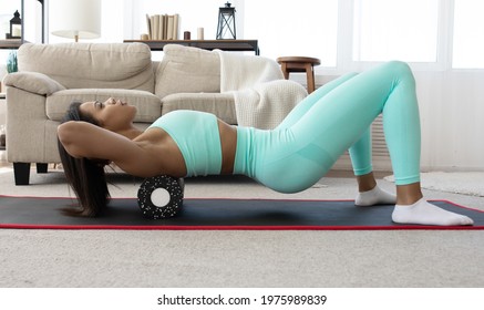 Fit Sporty Black Woman Wearing Sportswear Roll On Foam Myofascial Massage Roller Massaging Muscle On Yoga Mat Floor At Home. Active Girl Doing Fitness Workout Training Exercise In Living Room. MFR.