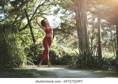 Fit sporty happy young Hispanic woman wearing sportswear meditating doing yoga breathing stretching exercises standing in nature park outdoors in sunny morning. Authentic candid photo. - Powered by Shutterstock