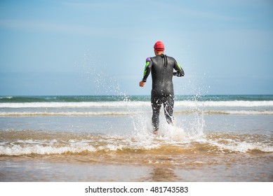 Fit Sporty Open Water Swimmer Man Running On The Shore Of A Beach For Warming Up Before Swimming Triathlon Competition Exercise Routine Workout. Male Nature Healthy Sport Lifestyle.