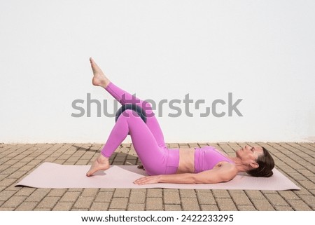 fit sporty woman doing pilates ball exercises outside. Toe tap exercise.