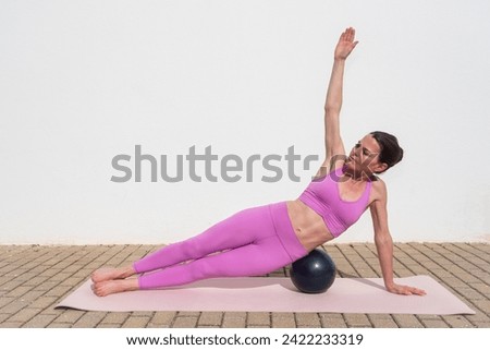 fit sporty woman doing pilates ball exercises outside. Side plank