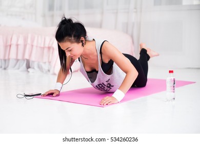 Fit Sporty Woman In Headphones Doing Push Ups Home Training Listening Music At Smartphone Concept Crossfit Fitness Workout Sport And Lifestyle.