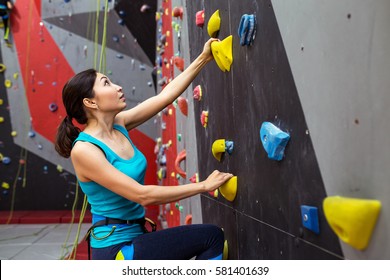 Fit Sporty Woman Looking Up At Rock Climbing Wall At The Gym And Training