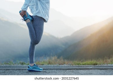 Fit stretch woman stretching quad leg muscle standing getting ready to run jogging outside. Athlete trail running in the mountains on a beautiful morning. - Shutterstock ID 2031227645
