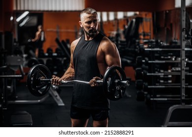 Fit Strong Man Doing Biceps Curl With Barbell In Gym