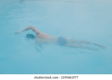 Fit Swimmer Male Training Swim Crawl In Open Winter Swimming Pool With Fog. Geothermal Outdoor Spa Health Concept.