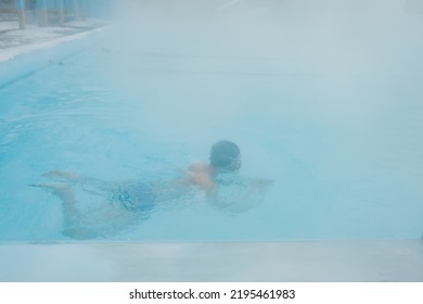 Fit Swimmer Male Training Swim In Open Winter Swimming Pool With Fog. Geothermal Outdoor Spa Health Concept.