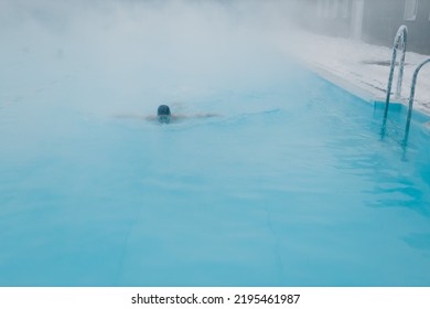 Fit Swimmer Male Training Swim In Open Winter Swimming Pool With Fog. Geothermal Outdoor Spa Health Concept.