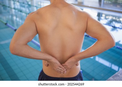 Fit swimmer touching his back by the pool at the leisure center - Powered by Shutterstock