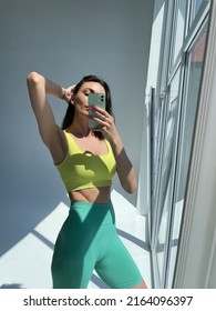 Fit Tanned Woman In Sportswear, Fitting Blue Leggings, Perfect Body, Abs Motivation, Take Photo Selfie On Phone In Mirror For Social Media, Stories, Vertical	