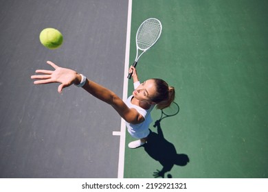 Fit tennis player, sport and serving during training, workout and exercise or match, game and competition from above. Sporty, active and healthy woman throwing a ball and practicing serve with - Powered by Shutterstock