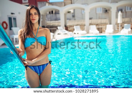 Fit woman in the bikini getting into the pool.Using hotel pool.Sunny day relaxation and leisure.Vacation pampering.Spa day.Hydro massage.Summer body care.Summer skin routine.Toned body exercise plan