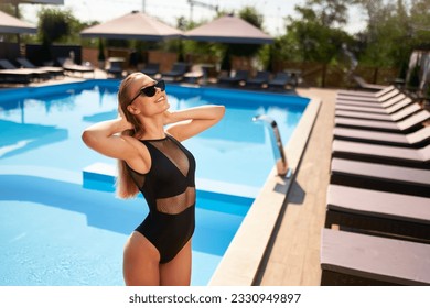 Fit woman in bikini sunbathing and chilling near swimming pool at a tropical spa. Attractive slim girl in swimwear and sunglasses posing at luxury resort. Hot female relaxing and enjoying the sun. - Powered by Shutterstock