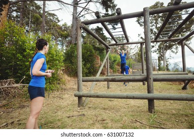 Fit woman climbing monkey bars in bootcamp - Powered by Shutterstock