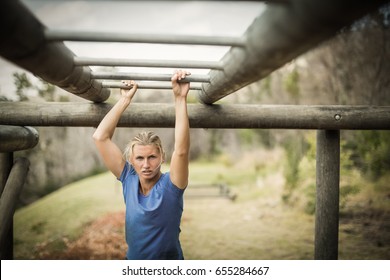 Fit woman climbing monkey bars during obstacle course in boot camp - Powered by Shutterstock