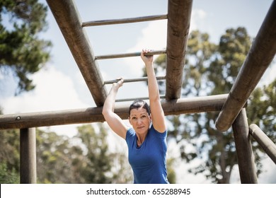 Fit woman climbing monkey bars during obstacle course in boot camp - Powered by Shutterstock