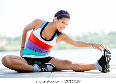 Fit wanita melakukan latihan peregangan di luar ruangan dan tersenyum Foto Stok