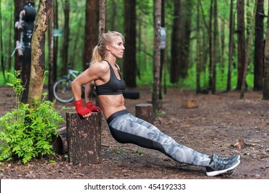 Fit woman doing triceps dips at park. Fitness girl exercising outdoors with own bodyweight.