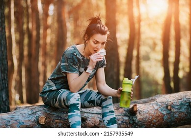 Fit Woman Eating Energy Granola Bar After Running At Sunset In The Forest