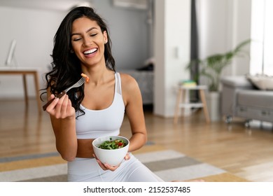 Fit woman eating healthy salad after working out at home