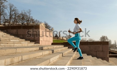 Fit woman in fitness clothes running upstairs outdoors, side view