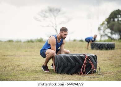 Fit woman flipping a tire during obstacle course in boot camp - Powered by Shutterstock