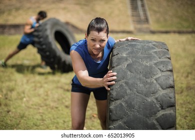 Fit woman flipping a tire during obstacle course in boot camp - Powered by Shutterstock