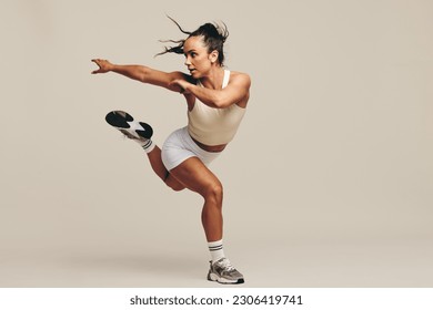 Fit woman having a strength training session in studio. Sporty young woman performing intense workout moves, demonstrating her dedication to a healthy and athletic lifestyle. - Powered by Shutterstock