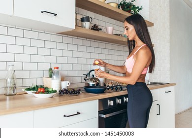 Fit Woman In Kitchen Cracking Egg Into Frying Pan Preparing Breakfast