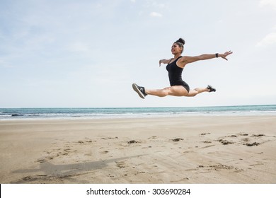 Fit woman leaping on the sand at the beach - Powered by Shutterstock