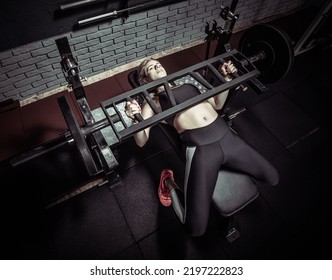 Fit Woman Lies On A Bench And Doing Barbell Press In A Modern Gym