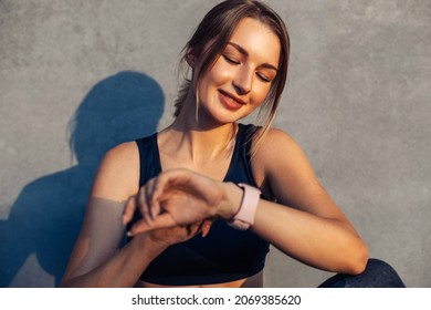 Fit woman looking at smartwatch and counting calories burned, Woman sitting relaxed after workout checking heart rate with smartwatch, Happy runner checking smartwatch after exercising outdoors - Powered by Shutterstock