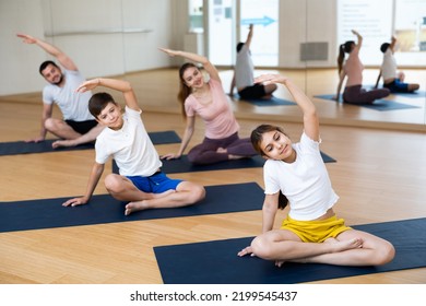 Fit Woman, Man And Teenage Girl And Boy Performing Yoga Exercises On Gymnastic Mats At Yoga Studio, Physical, Emotional And Spiritual Family Health Concept