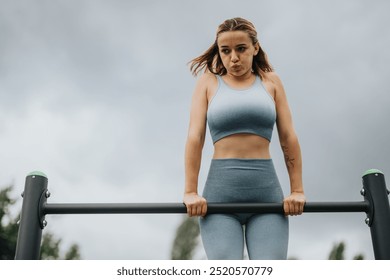 Fit woman performing pull-ups on an outdoor bar, focusing on biceps, shoulders, and lateral muscles. - Powered by Shutterstock