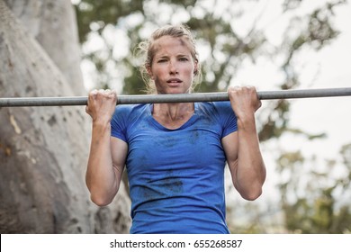 Fit woman performing pull-ups on bar during obstacle course in boot camp - Powered by Shutterstock