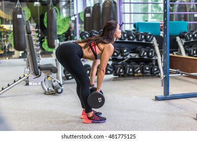 Fit Woman Performing Weight Lifting Deadlift Exercise With Dumbbell At Gym