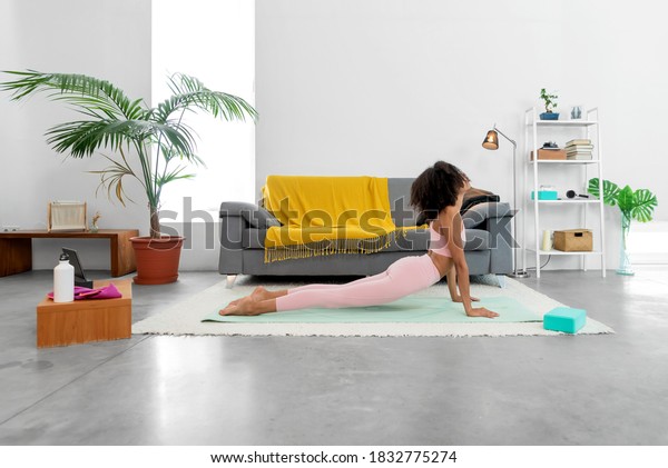 Fit woman practicing Cobra pose using\
online yoga training program in the tablet at\
home