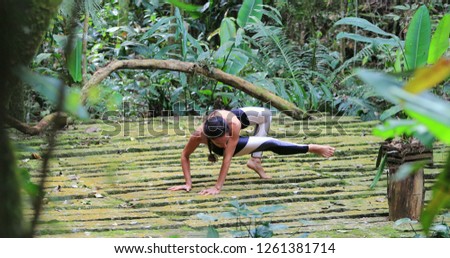 Fit woman practicing difficult yoga pose outdoors