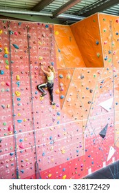 Fit Woman Rock Climbing Indoors At The Gym