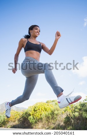Fit woman running along the open road on a sunny day in the countryside