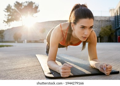 Fit woman showing endurance and stamina while doing planking pose. Strength training outdoors on yoga mat - Powered by Shutterstock