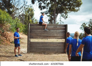 Fit woman sitting over wooden wall during obstacle course in bootcamp - Powered by Shutterstock