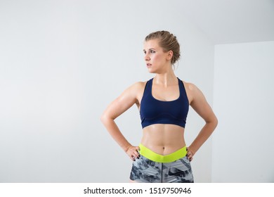 Fit woman in sporty clothes standing in a power pose, resting after workout. - Powered by Shutterstock