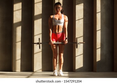 Fit Woman Standing With Barbell In Gym, Ready To Dead Lift