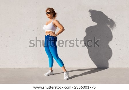 Fit woman standing with her old body left in shadow. Concept of body transformation through healthy diet and exercise.